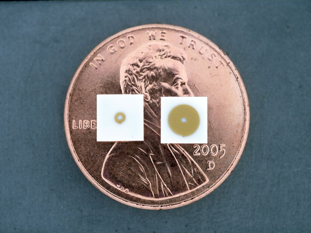 Gold electroformed micro coils on small substrates resting on a penny for scale